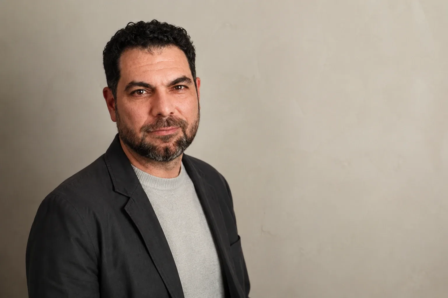 Dave Mercuri in a dark blazer against a pale wall